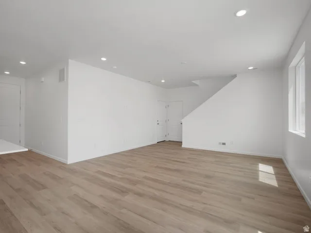 Open-concept living space featuring wood-finish flooring, recessed lighting, and white walls