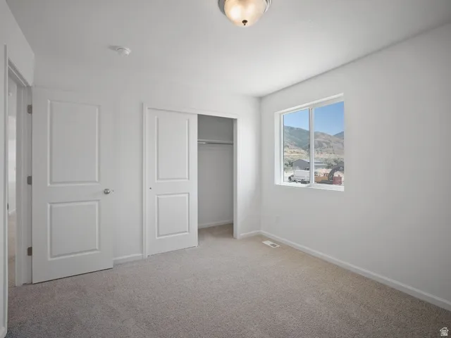 Carpeted room featuring a window with mountain scenery, a white paneled door, and a closet with sliding paneled doors