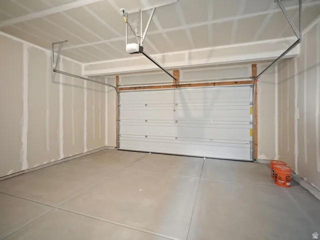 Spacious garage with a sectional overhead door, automatic opener, and concrete flooring