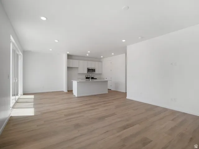 Spacious open-concept area featuring light wood-finish flooring and recessed lighting