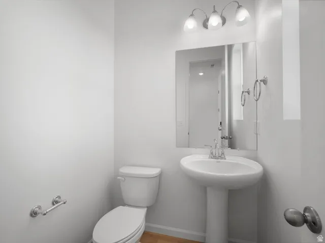 Pedestal sink with chrome faucet, a wall-mounted mirror, and a three-light vanity fixture