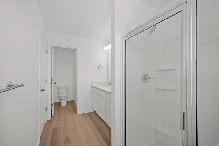 Shower enclosure with clear glass door, white surround, and chrome fixtures