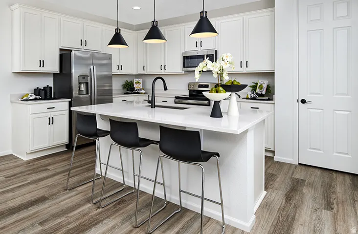 Modern kitchen featuring white cabinetry, light-toned countertops, stainless steel appliances, a center island with seating, and wood-finish flooring