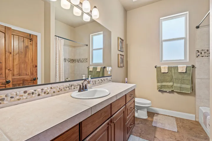 Vanity featuring an integrated sink, tile countertop, and wood-finish cabinetry