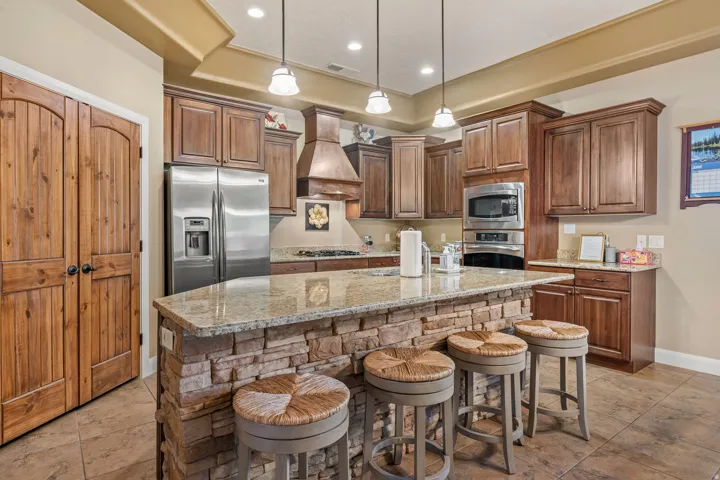 Kitchen featuring a stacked stone island with an integrated breakfast bar, granite countertops, and wood cabinetry