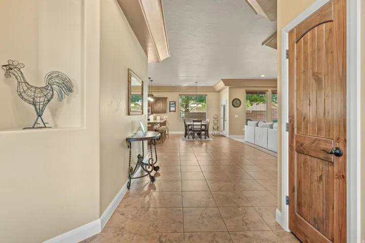 Tiled flooring extending throughout the open-concept living space, featuring a natural wood-paneled door with an arched top, multiple windows, and a built-in display niche
