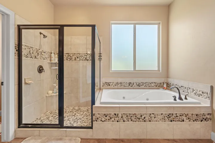Tiled shower with glass enclosure and pebble flooring