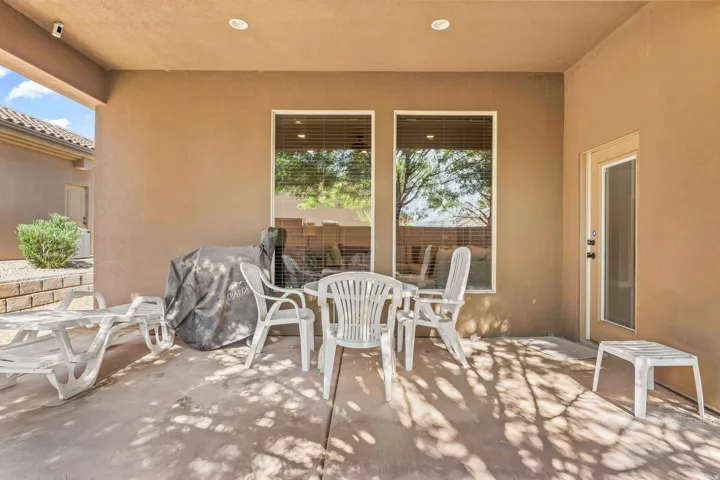 Covered concrete patio featuring recessed lighting, a door with a full-lite screen insert, and two large windows with horizontal blinds