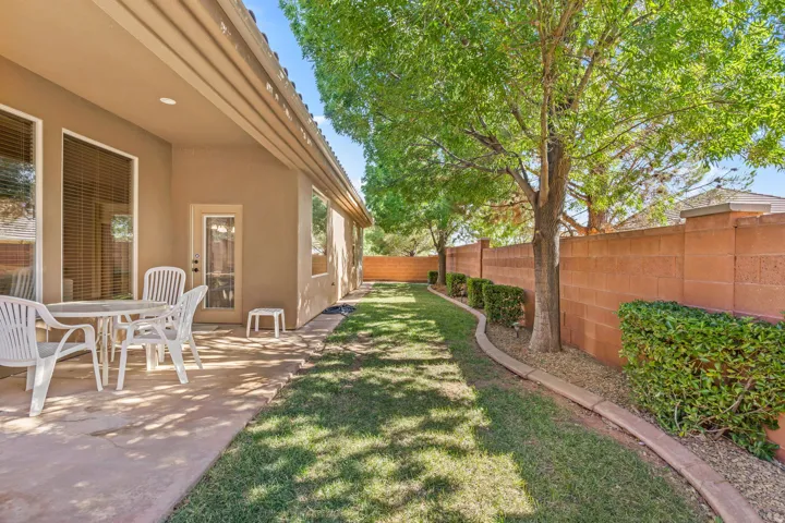 Expansive side yard featuring a manicured lawn, established trees, and perimeter block wall