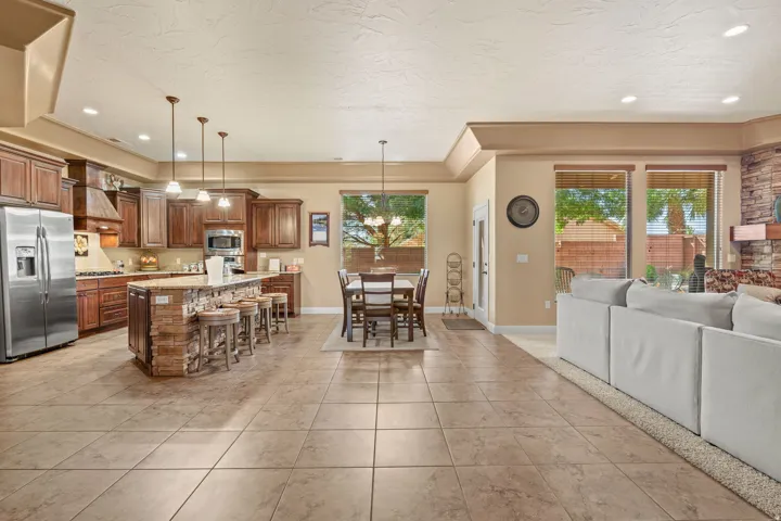 Spacious open-concept living area featuring a kitchen with wood cabinetry, stainless steel appliances, and a stone-clad island