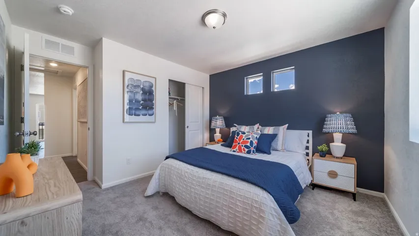 Carpeted bedroom featuring a deep blue accent wall, two horizontal windows, a built-in closet with sliding doors, and a ceiling-mounted light fixture