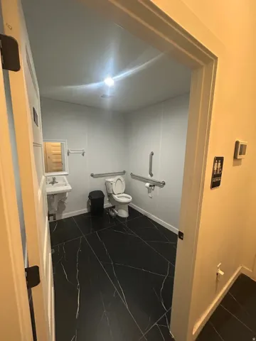 Restroom featuring black marble-look flooring, white walls, and a wall-mounted sink