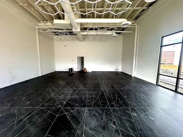 Spacious open-concept interior featuring large-format black tile flooring with white veining