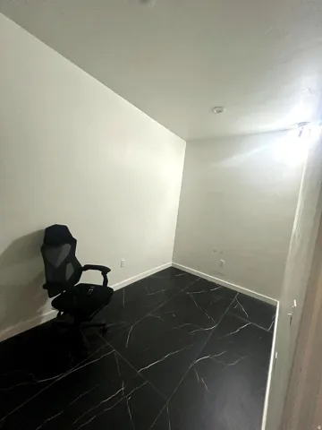 Room featuring dark-toned flooring with light veining, white baseboards, and light-toned walls