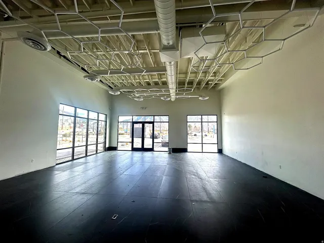 Spacious interior featuring exposed ceiling joists, hexagonal ceiling accents, and a wide entryway with double glass doors