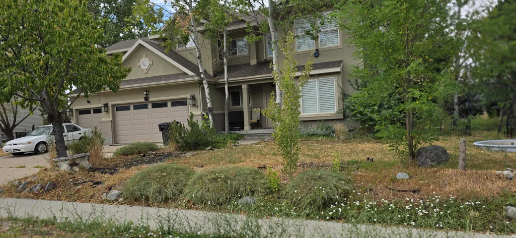 Two-story stucco exterior featuring a covered entry and attached three-car garage