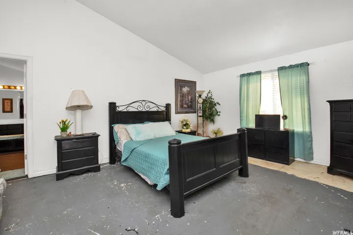 Spacious room featuring vaulted ceilings and a window with horizontal blinds