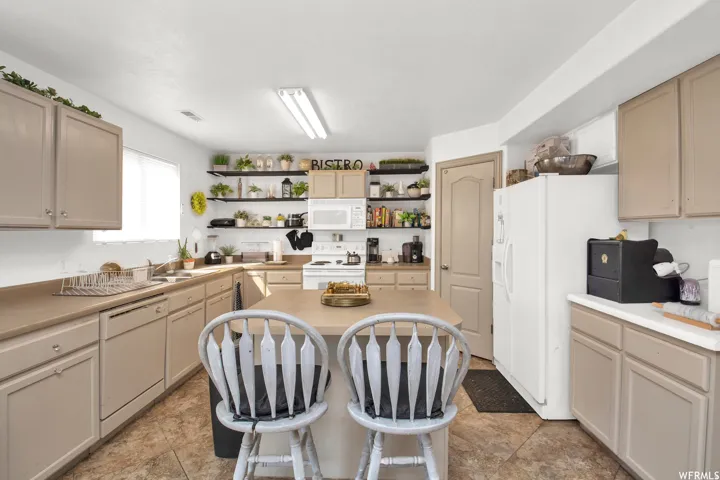 Kitchen featuring an island with seating, a white microwave, and built-in open shelving