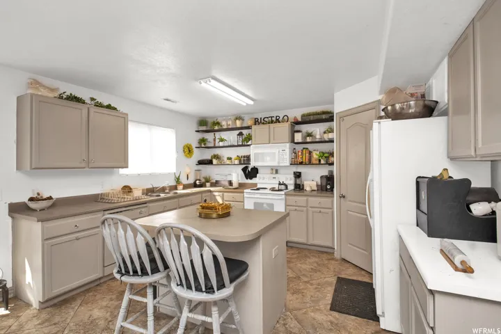 Kitchen featuring a center island with countertop seating, upper and lower cabinetry, open shelving, and a built-in oven with stovetop