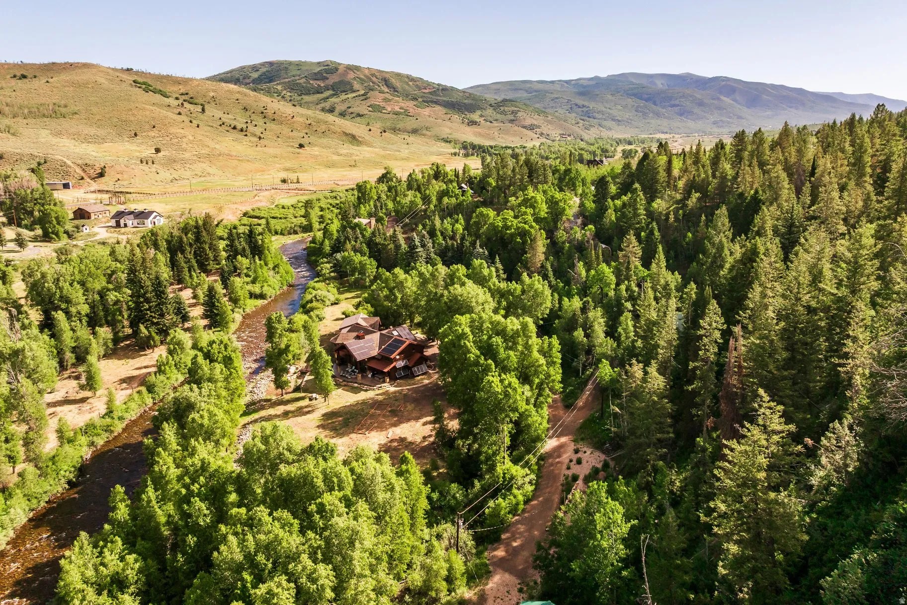 Expansive property featuring a river, mature trees, and a mountain backdrop