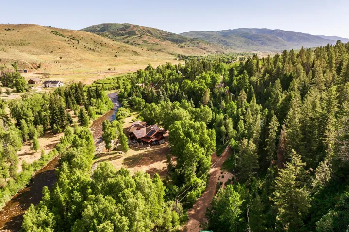 Expansive property featuring a river, mature trees, and a mountain backdrop