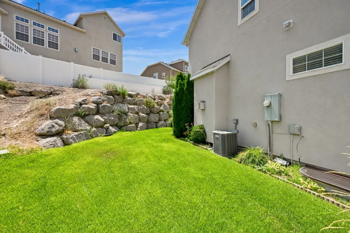 Expansive green lawn with a rock retaining wall and perimeter landscaping