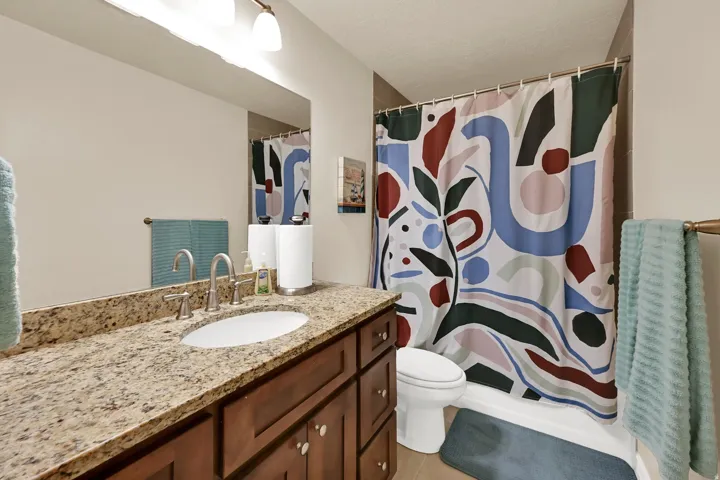 Bathroom featuring a vanity with a light granite-finish countertop, an undermount sink, and a brushed nickel faucet