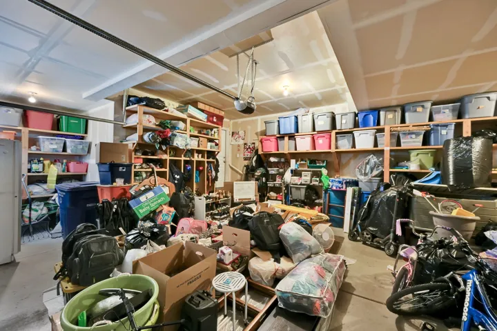 Garage interior with extensive built-in wooden shelving, overhead lighting, and exposed ceiling joists, providing ample storage potential