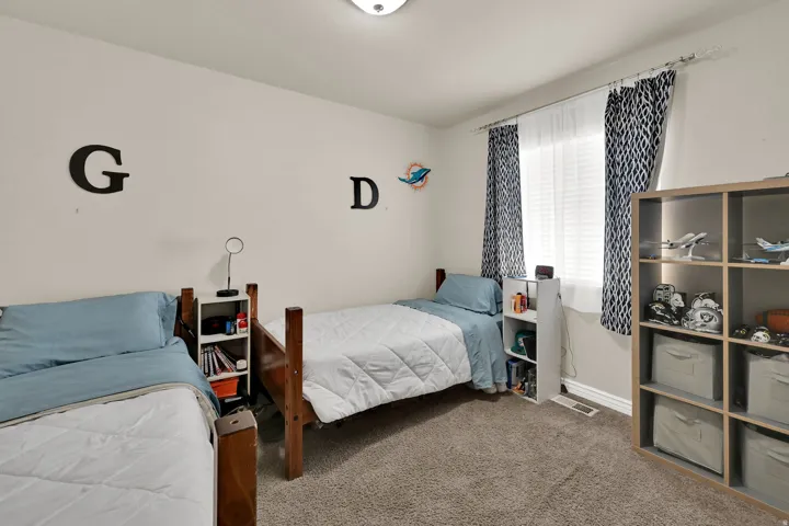 Carpeted room featuring a window with blinds and patterned drapes