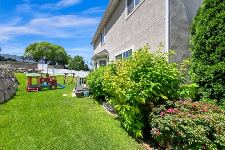 Expansive grass lawn bordered by a stone retaining wall and a white vinyl fence