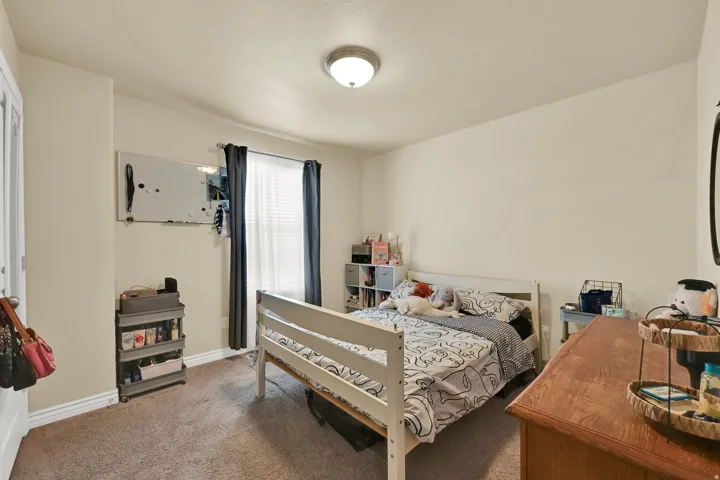 Carpeted room featuring a single window with blinds and dark curtains, a flush-mount ceiling light fixture, and light-toned walls