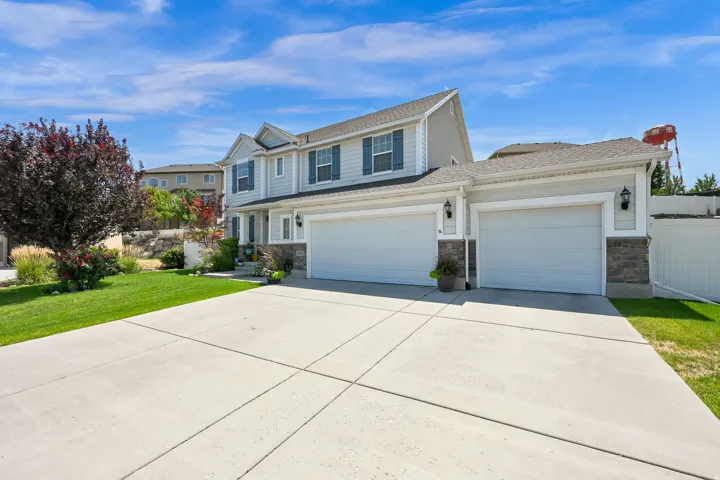 Two-story residence featuring light gray siding with dark blue window shutters, a two-car garage, and an additional single-car garage