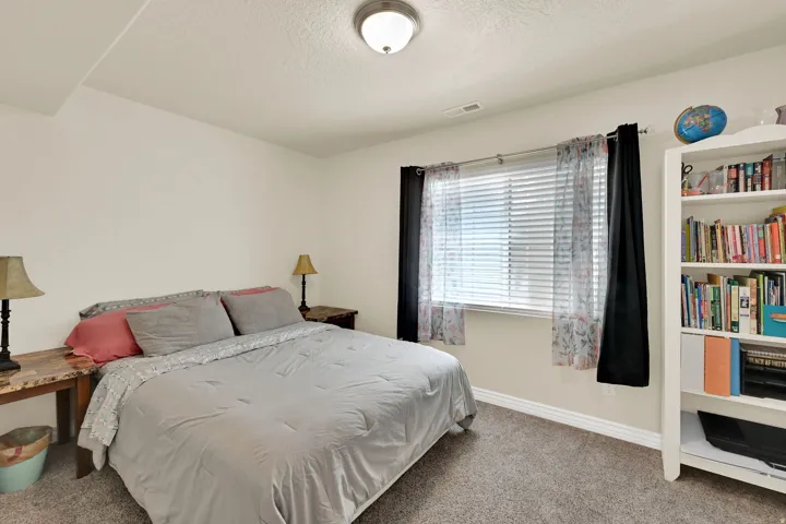 Carpeted room featuring a white ceiling and walls, a window with blinds, and white baseboards