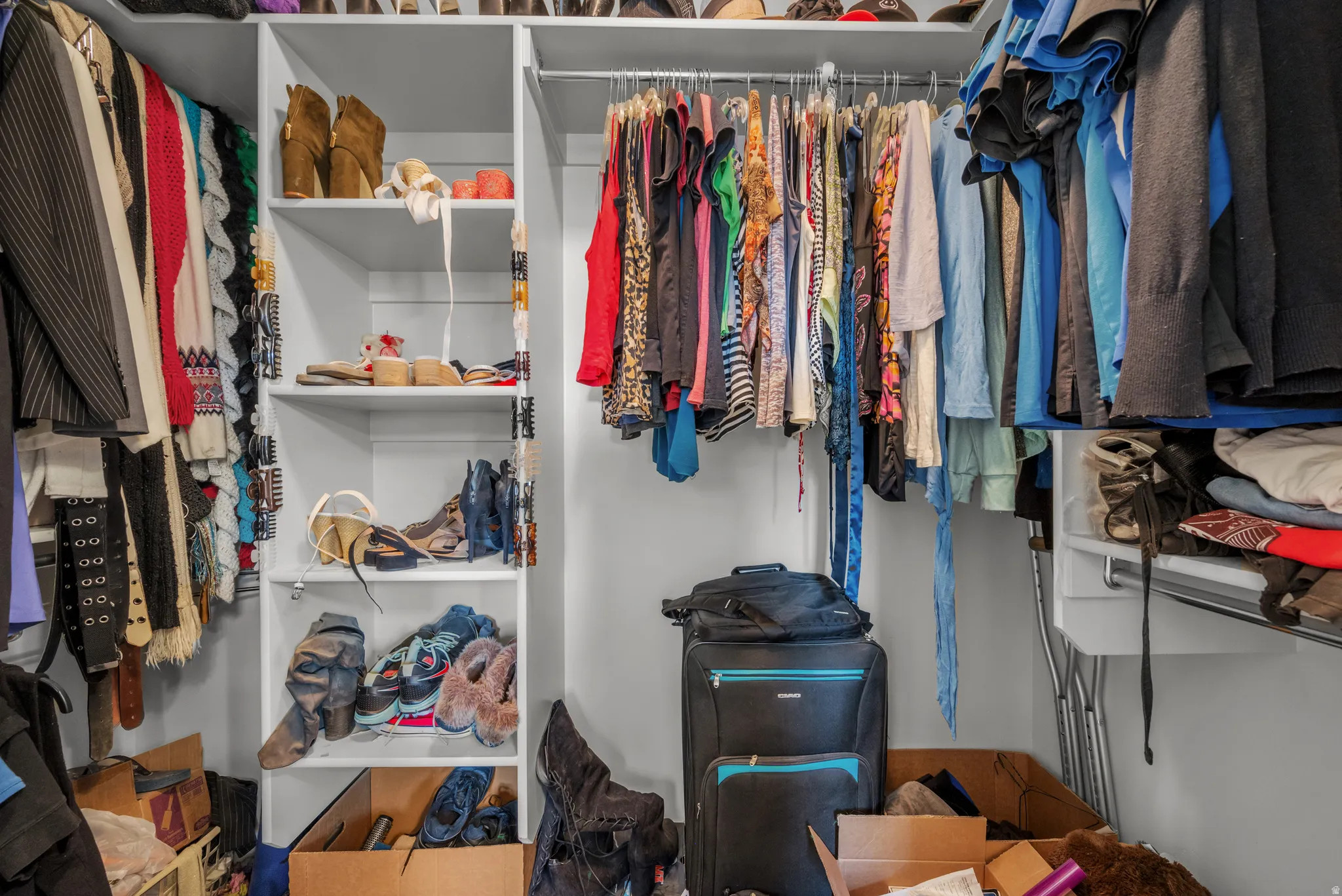Custom closet system featuring multiple hanging rods, adjustable shelving, and integrated storage solutions
