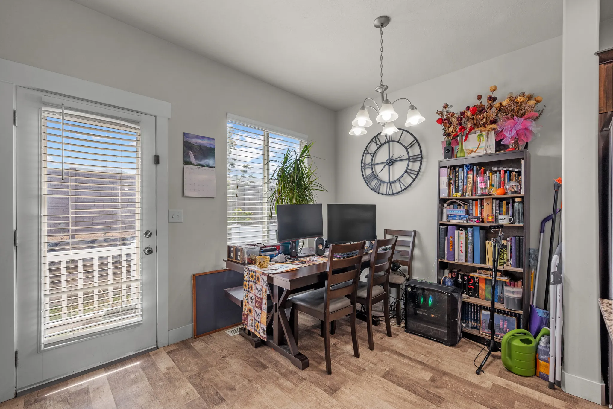 Bright interior space featuring wood-finish flooring, a glass-paned door, and large window with blinds