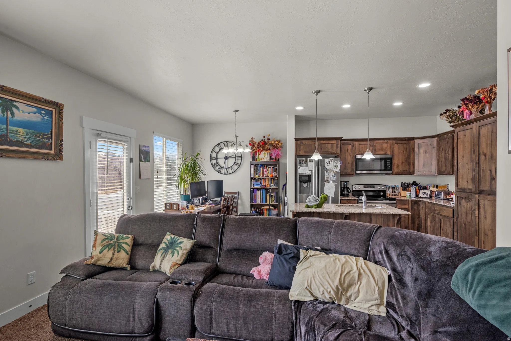 Open-concept living area with a kitchen featuring wood cabinetry and an island with pendant lighting