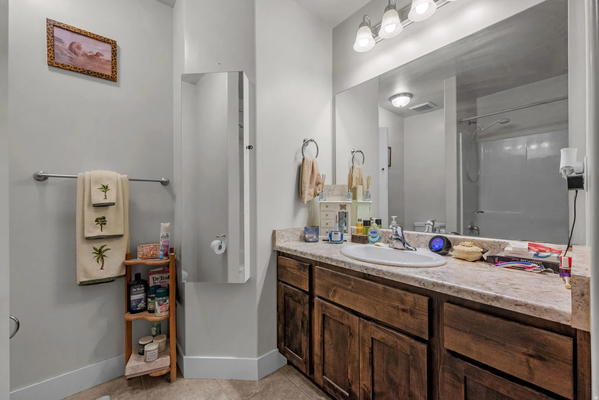 Bathroom featuring a wood-finish vanity with an integrated sink and a large wall-mounted mirror