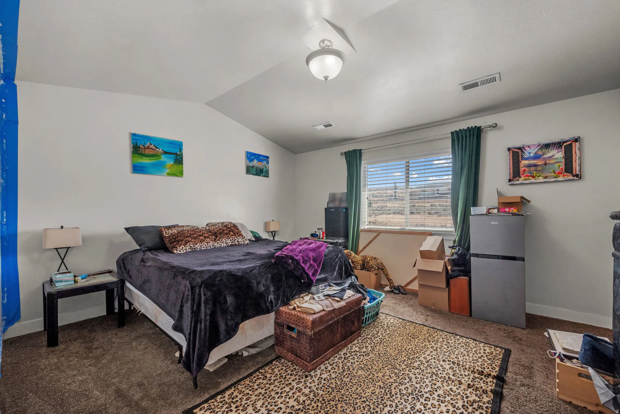 Spacious bedroom featuring vaulted ceilings, a ceiling fan, and a large window with blinds