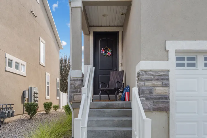 Front entry featuring a dark paneled door, concrete steps with white railings, and a stone facade accent