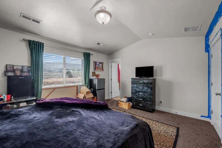 Carpeted room featuring a large window with horizontal blinds, a vaulted ceiling, and recessed lighting