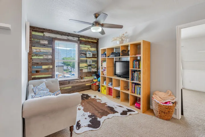 Accent wall featuring multicolored reclaimed wood planks, a window with blinds, and a built-in shelf unit