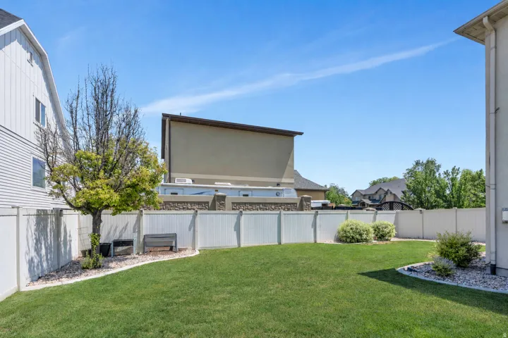 Expansive grassy yard area with a white privacy fence
