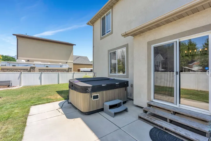 Private backyard featuring a hot tub on a concrete patio