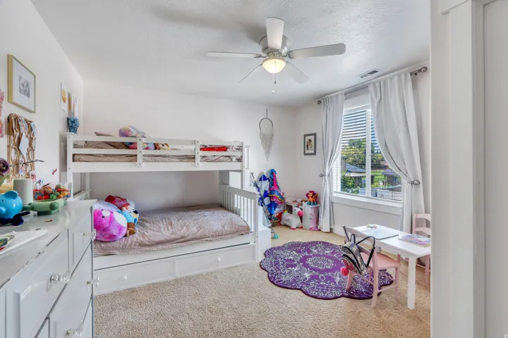 Carpeted room featuring a ceiling fan with integrated lighting, a window with blinds and drapes, and white baseboards