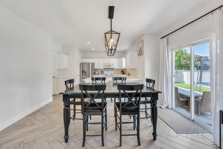 Open-concept dining area featuring wood-finish flooring in a herringbone pattern and a contemporary linear pendant light fixture
