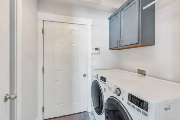 Laundry area featuring light gray walls, white trim, and a white paneled door