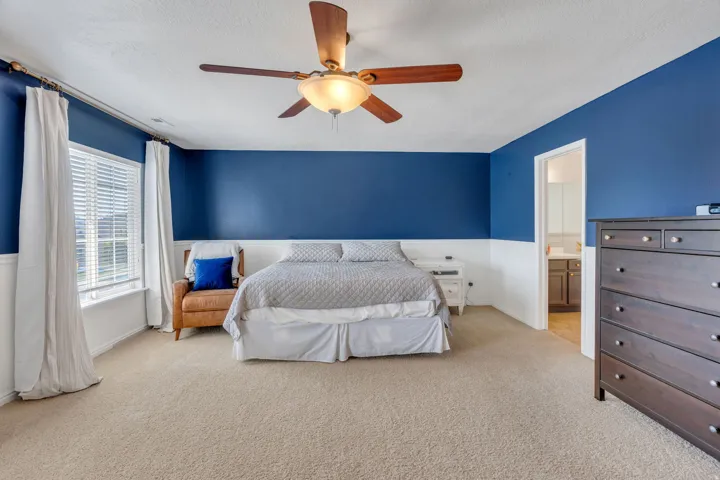 Room featuring a wood-finish ceiling fan, wall-to-wall carpeting, and a window with blinds and drapes