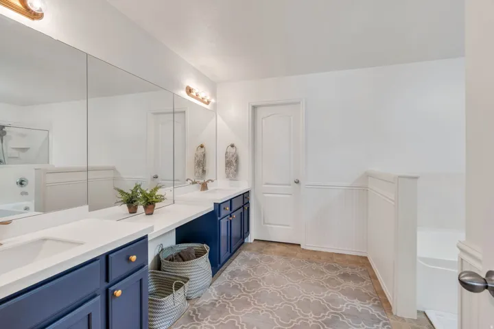 Dual vanity with white countertops and navy cabinetry