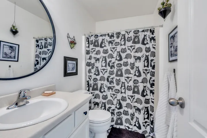 White bathroom featuring a single vanity with a white ceramic sink, polished chrome faucet, and integrated countertop