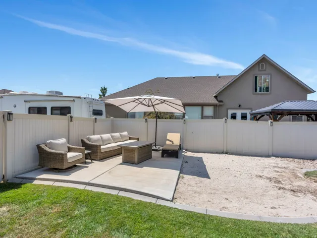Expansive outdoor space featuring a concrete patio, white vinyl fencing, a privacy gate, and a dedicated area for landscaping
